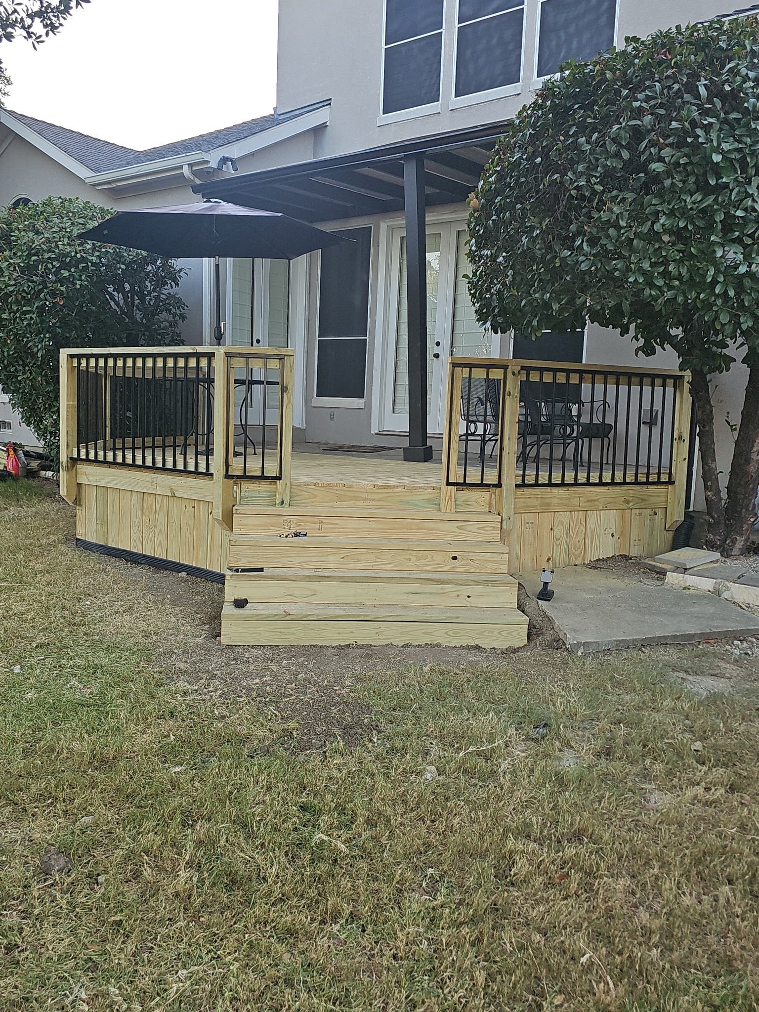 Raised wood deck with stairs and black metal railing